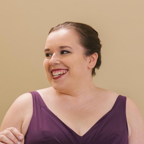 Holly in a bridesmaid dress, looking left and smiling
